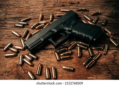 Portrait of a black 9mm pistol on an old wooden floor with 9mm ammunition next to it. top view
