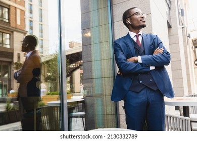 Portrait Of Black African American Businessman In Suit Outdoors Posing While Standing Near Panoramic Shop Window Reflecting In Glass