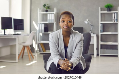 Portrait Of Black Business Woman In Suit Sitting On Office Chair Looking At You With Face Expression That Could Be Interpreted As Both Disappointed Unimpressed And Impressed 'Hmm Not Bad' Expression