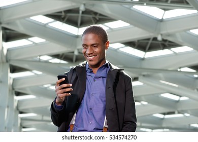 Portrait Of Black Businessman Smiling And Looking At Mobile Phone