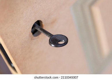 A portrait of a black design key in an unfinished mdf door. The design part of the key hole is not installed yet and the door is not painted yet. The lock is already present in the door.