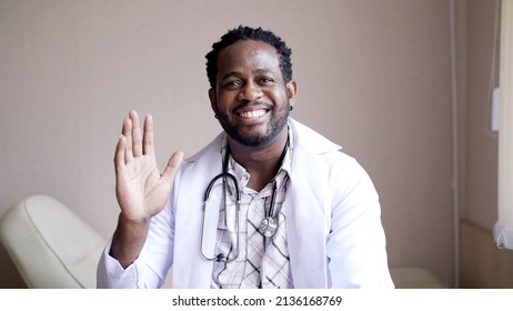 Portrait Black Doctor In Medical Gown Speaking To Camera With Happy Face To Present Medical Treatment Of Hospital In Examination Room. Black Physician Give Consulting To Camera.
