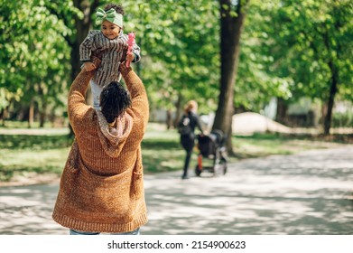 Portrait Of A Black Father And Young Daughter Playing In The Park. Little African American Baby Girl Smiling And Having Fun Moments With Her Dad. Father Lifting His Little Daughter Up In The Air.