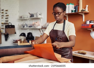 Portrait of black female artisan creating handmade leather pieces in shop and working with genuine leather - Powered by Shutterstock