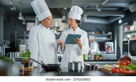 Portrait Of Black Female Chef Takes Fresh Herb, Enjoys Smell With A Smile, Secret Ingredient That Makes Grandmother's Recipe Special. Traditional Restaurant Kitchen With Authentic Dish, Healthy Food