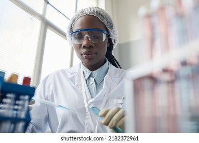 Portrait Of Black Female Scientist Wearing Protective Glasses While Doing Experiments In Lab