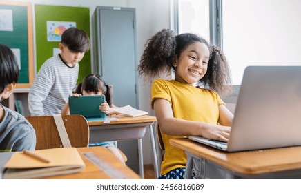 Portrait of black girl using computer to learn lessons in elementary school. Student boy studying in primary. Children with gadgets in classroom. Education knowledge, technology internet network. - Powered by Shutterstock