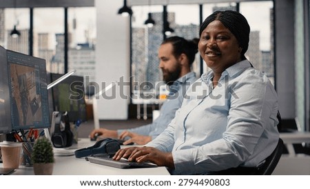 Portrait of black interior designer using high tech software for modern layout, 3D modeling program to design construction floor plan. Architectural blueprints on dual monitors, virtual assets.