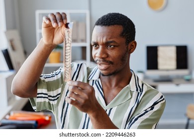 Portrait Of Black Male Photographer Looking At Film Against Light And Making Selection While Working In Photo Studio