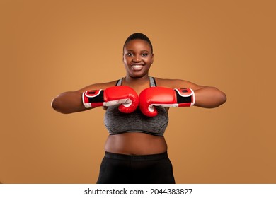 Portrait Of Black Millennial Woman In Sportswear Wearing And Putting Together Red Boxing Gloves, Confident Young African American Lady Ready For Box Training, Looking At Camera Posing - Powered by Shutterstock