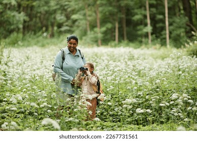 Portrait of black mother and daughter hiking in nature and looking in binoculars, copy space  - Shutterstock ID 2267731561