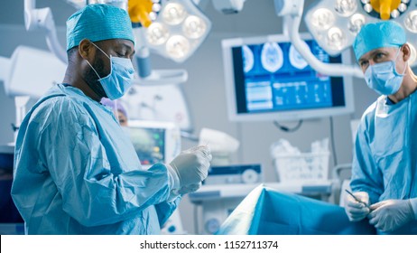 Portrait of the Black Professional Surgeon Performing Invasive Surgery on a Patient in the Hospital Operating Room. In the Background Modern Hospital Operating Room.