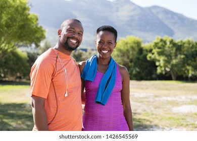 Portrait Of Black Sporty Couple Looking At Camera At Park With Copy Space. Happy Mature Man And Smiling Woman Relaxing After Jogging In The Park. African American Man And Woman Resting After Exercise.