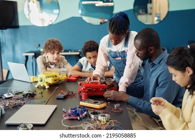 Portrait of black teenage girl building robot with diverse group of children during engineering class in school - Powered by Shutterstock