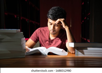 Portrait Of Black Thai Asian Guy Wear Red Shirt Make Serious Face Reading A Lot Of Book In Library Stock Photo