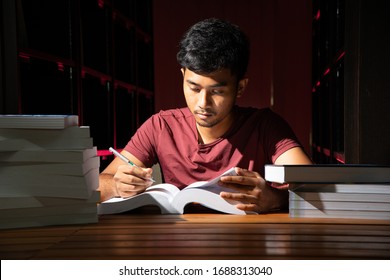 Portrait Of Black Thai Asian Guy Wear Red Shirt Make Serious Face Reading A Lot Of Book In Library Stock Photo