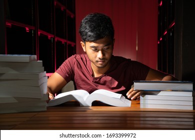 Portrait Of Black Thai Asian Guy Wear Red Shirt Make Serious Face Reading A Lot Of Book In Library Stock Photo