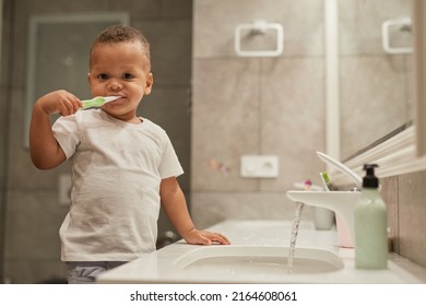 Portrait Of Black Toddler Boy Brushing Teeth In Bathroom And Looking At Camera, Copy Space