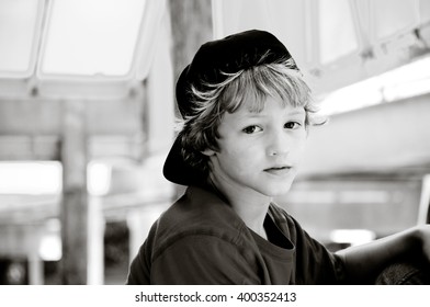 Portrait In Black And White Of Cute Kid With Long Curly Hair Looking Sad At Camera.