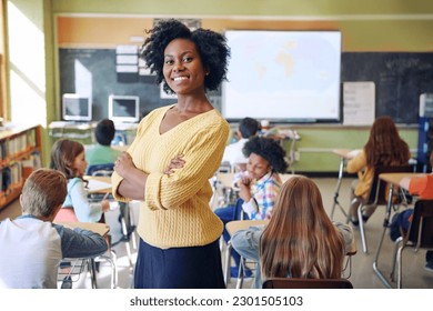 Portrait, black woman and teacher with arms crossed, students or happiness in a classroom. Face, female educator or employee with children, smile or education with knowledge, learners and development - Powered by Shutterstock