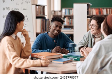 Portrait of Black young man smiling during group discussion with students in college library - Powered by Shutterstock