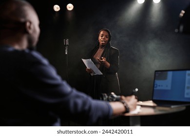 Portrait of Black young woman performing on stage with theater director watching rehearsal or casting process copy space - Powered by Shutterstock