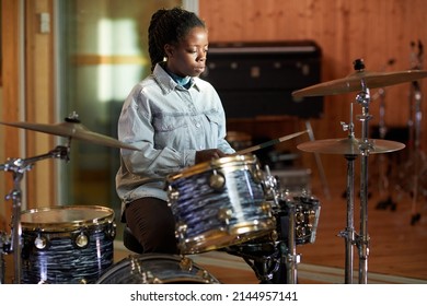 Portrait Of Black Young Woman Playing Drums Alone While Practicing In Music Studio With Sun Accent, Copy Space