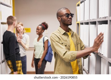 Portrait of blind African-American man choosing book in library