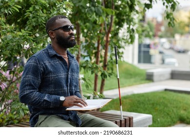 Portrait Of Blind Man Wearing Sunglasses And Reading Book In Braille Outdoors, Copy Space