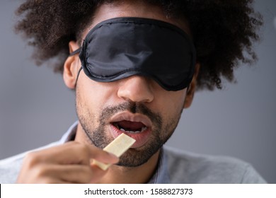 Portrait Of Blindfolded Young Man Testing Food