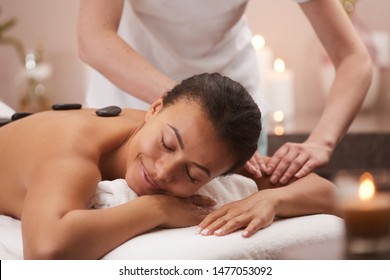 Portrait of blissful young woman smiling happily while enjoying stone therapy in spa, copy space