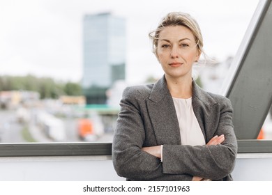 Portrait Of A Blond Mature Business Woman In A Gray Jacket On A Modern Urban And Office Buildings Background