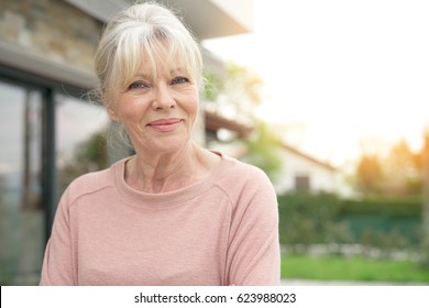 Portrait of blond senior woman sitting in front of new house
