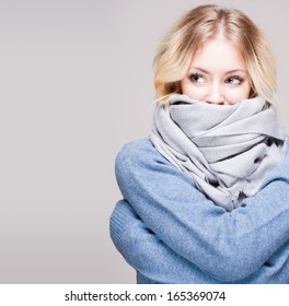 Portrait of blond winter beauty in light blue sweater and scarf.