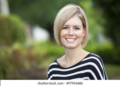 Portrait Of A Blond Woman Smiling At The Camera Outside