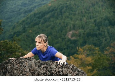 Portrait Of A Blonde Athlete Woman While Climbing A High Mountain, Overcoming Obstacles On The Way Up 