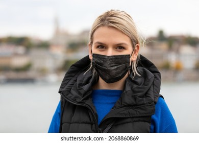 Portrait Of Blonde Caucasian Woman Wearing A Black Surgical Mask Outdoor In The City Because Of Covid-19 Pandemic