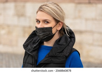 Portrait Of Blonde Caucasian Woman Wearing A Black Surgical Mask Outdoor In The City Because Of Covid-19 Pandemic