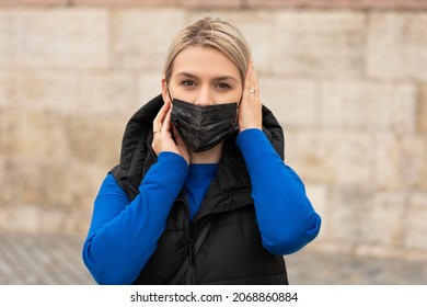 Portrait Of Blonde Caucasian Woman Wearing A Black Surgical Mask Outdoor In The City Because Of Covid-19 Pandemic