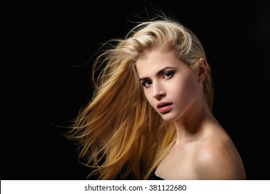 Portrait of blonde girl with flying hair on black background