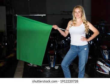 Portrait Of Blonde Girl Holding Green Flag At Kart Racing Track