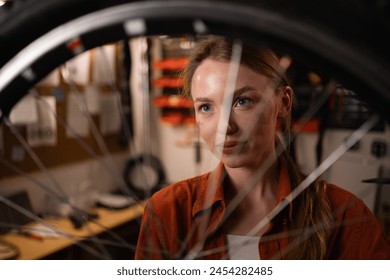 Portrait of a blonde girl repairing a bicycle with a bicycle wheel in her hands. Bicycle maintenance and repair concept. Copy space - Powered by Shutterstock