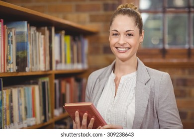 Portrait Of Blonde Teacher Holding Book In The Library In School