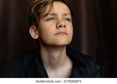 Portrait Of Blonde Teenage Boy On Dark Background Outdoor. Low Key Close Up Shot Of A Young Teen Boy, Adolescence. Selective Focus. Loneliness, Sadness, Adolescent Anxiety, Emotional.