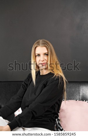 Portrait of a blonde woman in a black jumper. Copy space