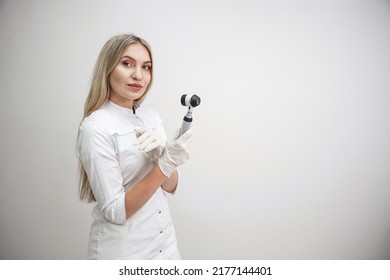 Portrait of blonde woman dermatologist with dermatoscope in white lab coat and white gloves on the white background