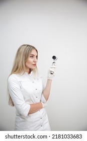 Portrait of blonde woman dermatologist with dermatoscope in white lab coat and white gloves on the white background. 