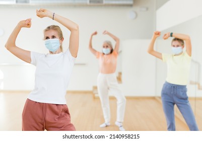 Portrait Of Blonde Woman In Face Mask Dancing During Group Class In Dance Studio