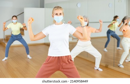 Portrait Of Blonde Woman In Face Mask Dancing During Group Class In Dance Studio