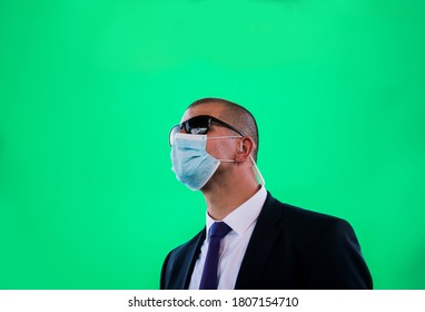 Portrait Of Bodyguard Man With Earphone And Black Eyeglasses And Business Suit Isolated On Green Background